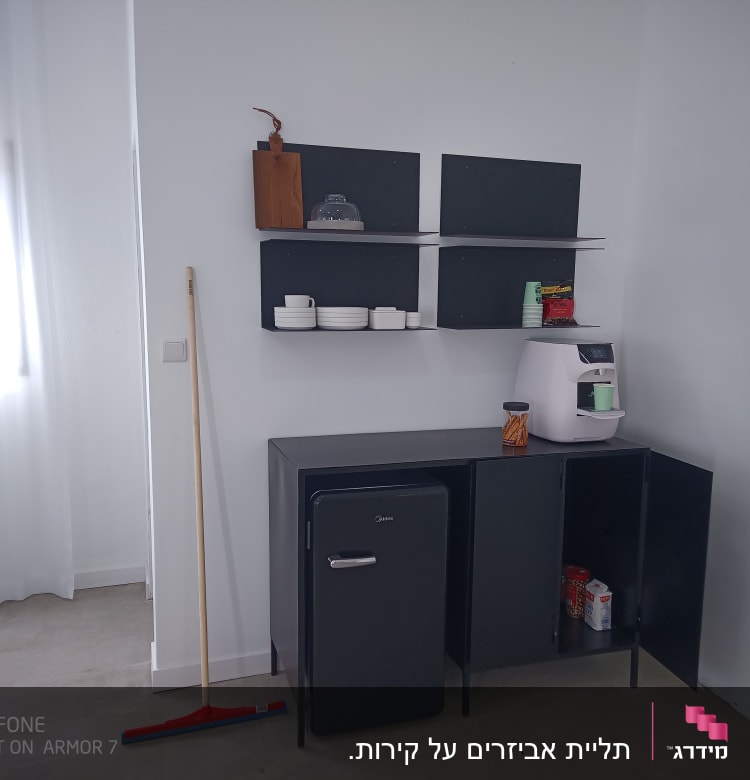 מטאטא עומד ליד ארון שחור עם מדפים
